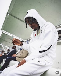 a man in a white hoodie sitting on a bench